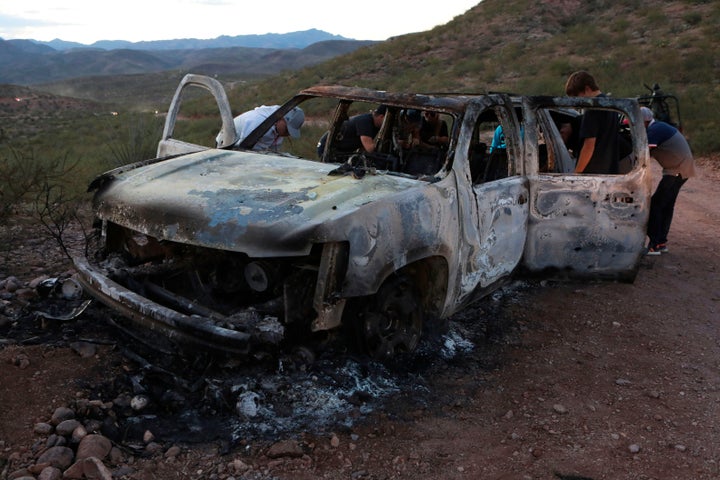Members of the Lebaron family examine the burned car where some of the nine murdered members of the family were killed and bu