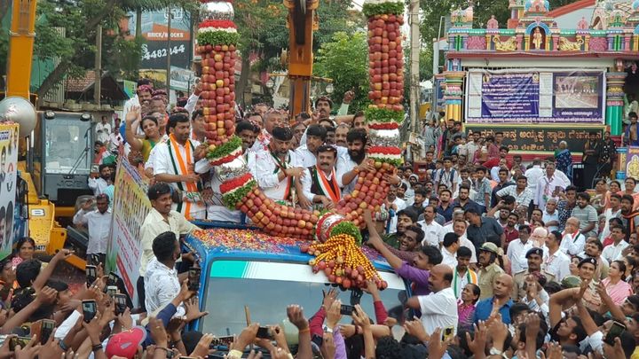 An apple garland being lowered around Congress leader D.K. Shivakumar. Apple garlands have now become common in Karnataka, and many leaders are welcomed with these instead of flower garlands. Each garland has around 3,000 apples, and a crane is used to lower it around the leader's head. 