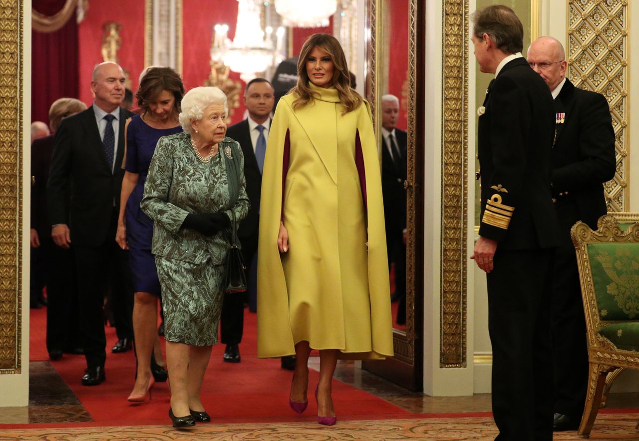 Η Μελάνια Τραμπ φόρεσε μια κίτρινη δημιουργία, με μωβ λεπτομέρειες στο εσωτερικό και μωβ γόβες.