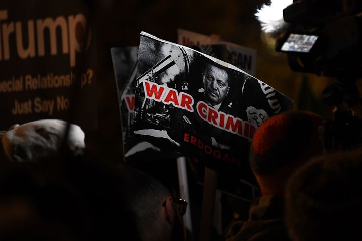 Το πορτρέτο του Ερντογάν και από κάτω οι λέξεις "εγκλήματα πολέμου" σε πλακάτ στα χέρια διαδηλωτή, τις ώρες της συνόδου κορυφής του ΝΑΤΟ στο Λονδίνο (AP Photo/Alberto Pezzali)