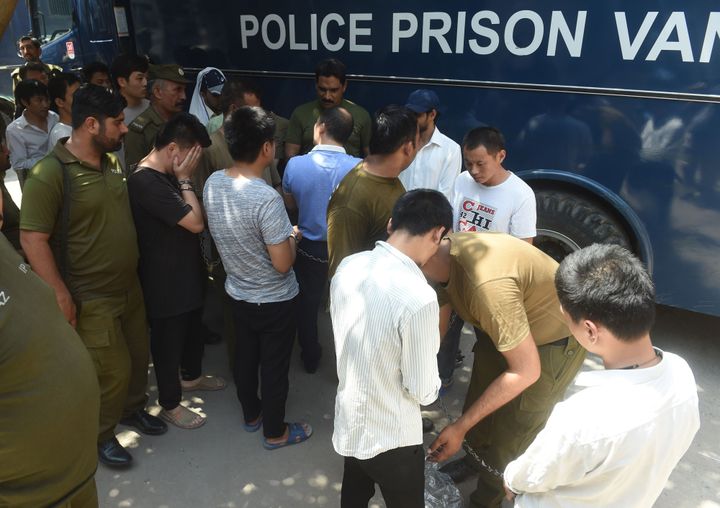 Pakistani policemen escort handcuffed Chinese nationals as they arrive in court in Lahore on June 10, 2019. The men are accused of allegedly luring young Pakistani girls into fake marriages and forcing them into prostitution in China.