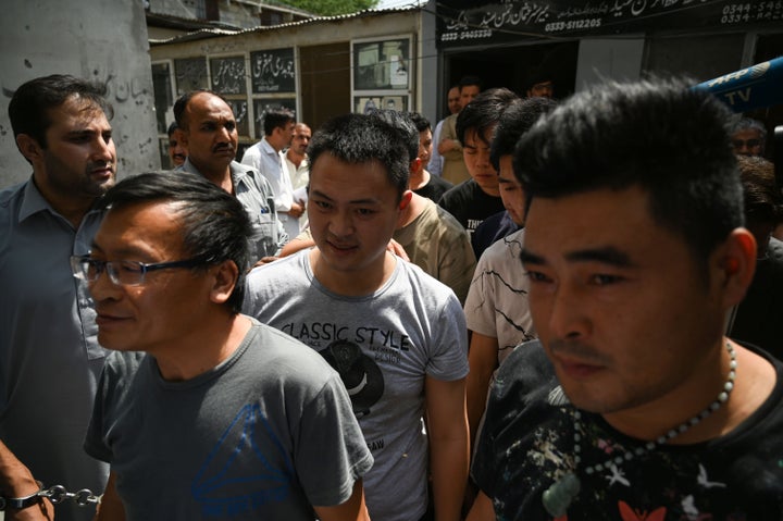 Detained Chinese nationals walk together as they arrive at a court in Islamabad after being arrested by the Pakistani Federal