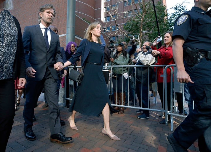 Felicity Huffman leaves federal court with her husband, William H. Macy, wearing a navy dress and jacket on Sept. 13, 2019, in Boston.