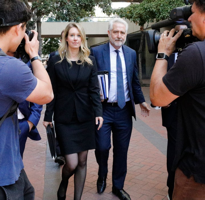 Elizabeth Holmes leaves a federal court after a status hearing on July 17, 2019, wearing a black dress and jacket.