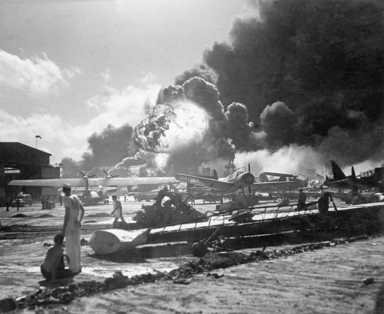 日本海軍機動部隊から発進した航空部隊の奇襲攻撃を受けつつある米ハワイ諸島オアフ島真珠湾内にあるフォード島基地。手前は水上機、飛行艇基地。爆発あるいは炎上しているのは艦船群（アメリカ・ハワイ）12月7日