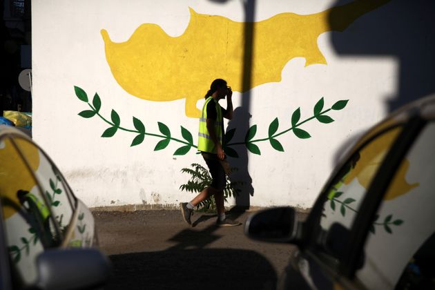 A man walks past a Cypriot flag painted on a wall in Nicosia, Cyprus July 7, 2017. REUTERS/Yiannis Kourtoglou