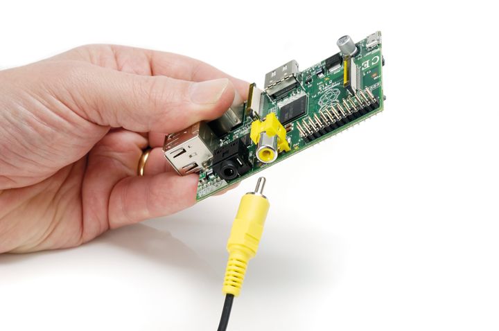 Detail of hands inserting an RCA video connector into a Raspberry Pi Model B single-board computer photographed on white, taken on June 14, 2012.