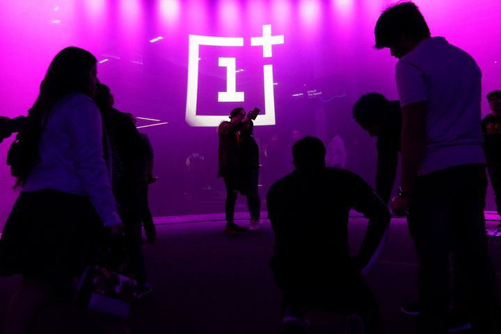 The OnePlus logo is projected onto a wall during a launch event.