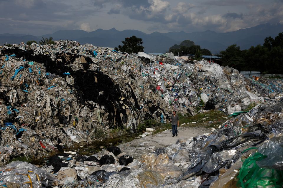 A man walks through an illegal dumpsite teeming with plastic trash imported from the United States, in...