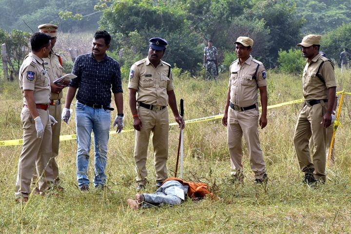 Police personnel stand next to the body of a man at the site where Police officers shot dead four detained gang-rape and murder suspects in Shadnagar, some 55 kilometres (34 miles) from Hyderabad, on December 6, 2019