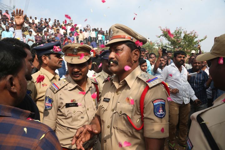 People throw flower petals on the policemen guarding the area where rape accused were shot, in Shadnagar some 50 kilometers from Hyderabad, Friday, Dec. 6, 2019. 