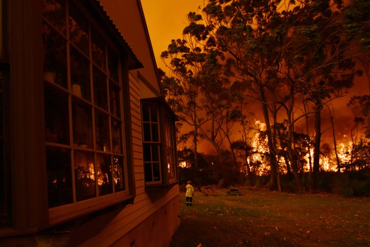 Fire fighting crews from the Rural Fire Service (RFS), NSW Fire and Rescue and National Parks and Wildlife Service (NPWS) officers fight a bushfire encroaching on properties near Lake Tabourie, Australia, December, 5, 2019. AAP Image/Dean Lewins/via REUTERS