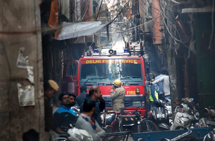 A fire engine stands by the site of a fire in an alleyway, tangled in electrical wire and too narrow for vehicles to access,