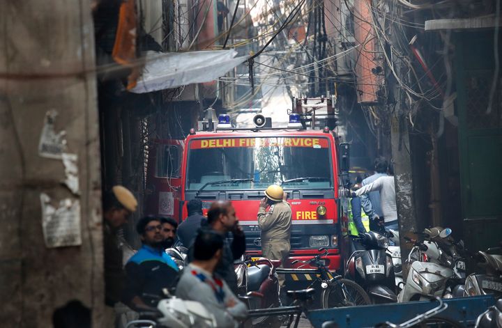 A fire engine stands by the site of a fire in an alleyway, tangled in electrical wire and too narrow for vehicles to access, in New Delhi, India, Sunday, Dec. 8, 2019. Dozens of people died on Sunday in a devastating fire at a building in a crowded grains market area in central New Delhi, police said. 