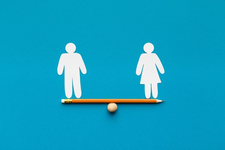 Gender equality in corporate world. Figures of man and woman on pencil seesaw, blue background, copy space