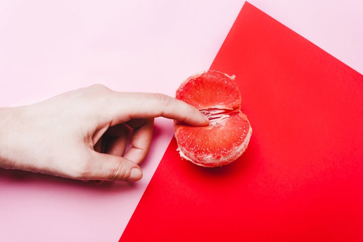 Concept sex, masturbation. Hand, fingers in grapefruit, vagina symbol on a red background