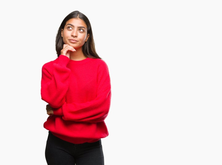 Young beautiful arab woman wearing winter sweater over isolated background with hand on chin thinking about question, pensive expression. Smiling with thoughtful face. Doubt concept.