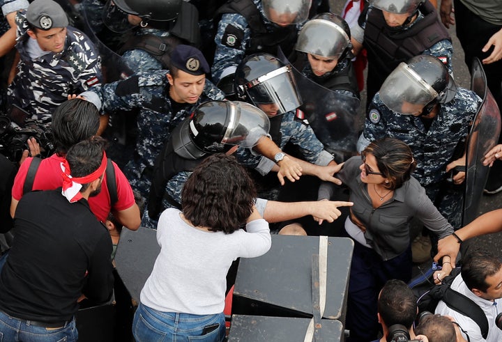 In this Friday Oct. 25, 2019, MTV television reporter Nawal Berry, right, is protected by riot policemen after she was attack