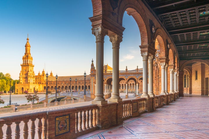 Sunrise on the old tower seen from colonnade of the semi-circular portico, Plaza de Espana, Seville, Andalusia, Spain