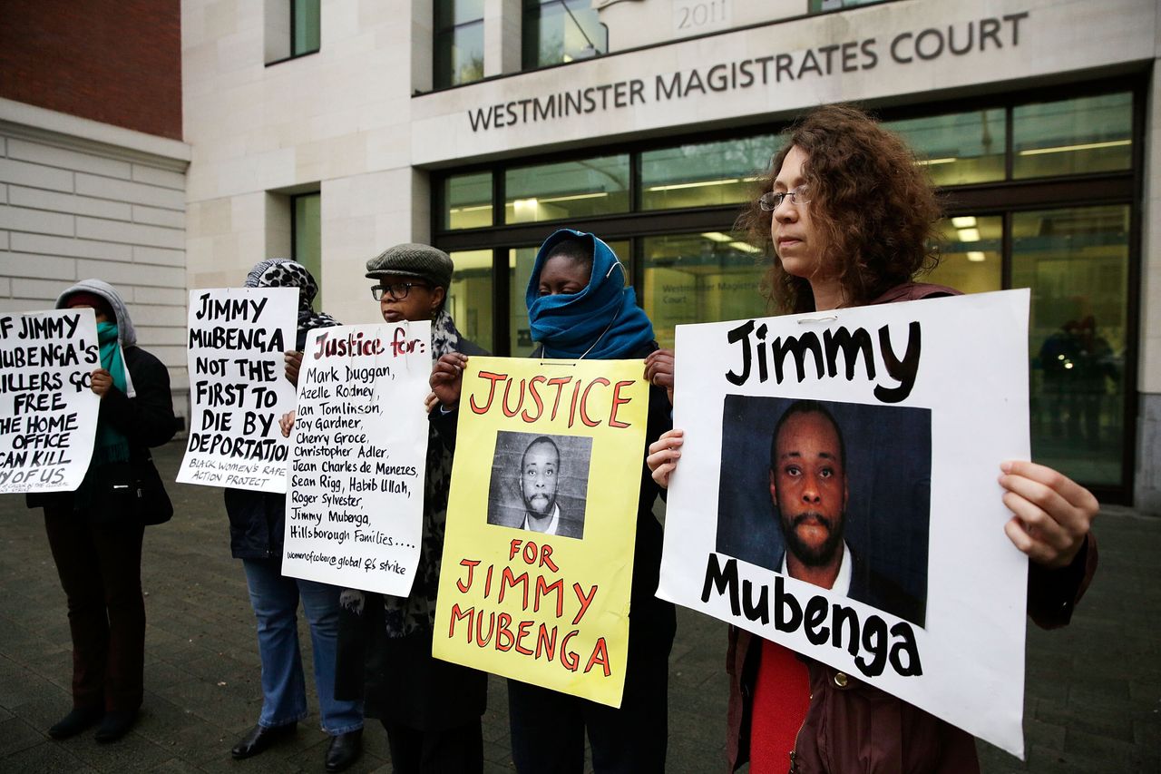Supporters of Jimmy Mubenga's family pose with placards outside Westminster Magistrates Court.