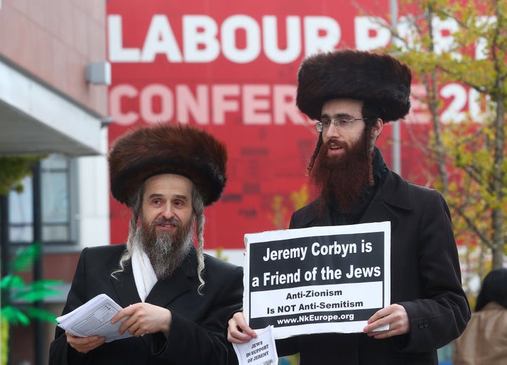 Two men wearing Orthodox Jewish attire hold placards and leaflets in support of Labour Party leader Jeremy Corbyn outside the party's conference in Liverpool, Britain, on Sept. 26, 2018. 