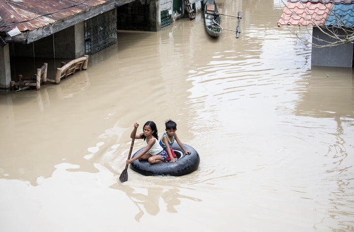 Children use a tire to cross a flooded street in the aftermath of Typhoon Mangkhut in September 2018.