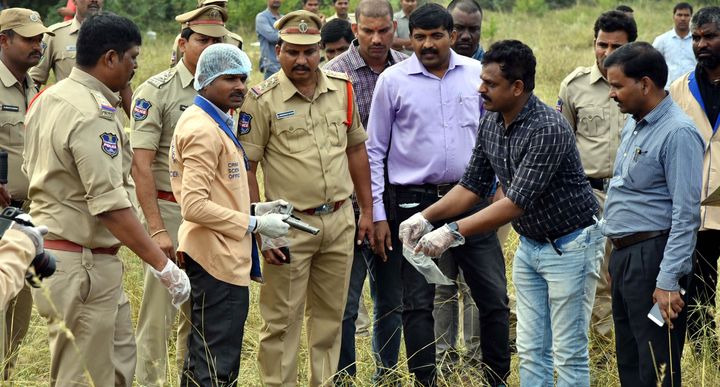 A forensic official ((3L) holds a gun as police officers gather around the body of man at the site where police officers shot dead four detained gang-rape and murder suspects in Shadnagar, some 55 kilometres from Hyderabad, on December 6, 2019.