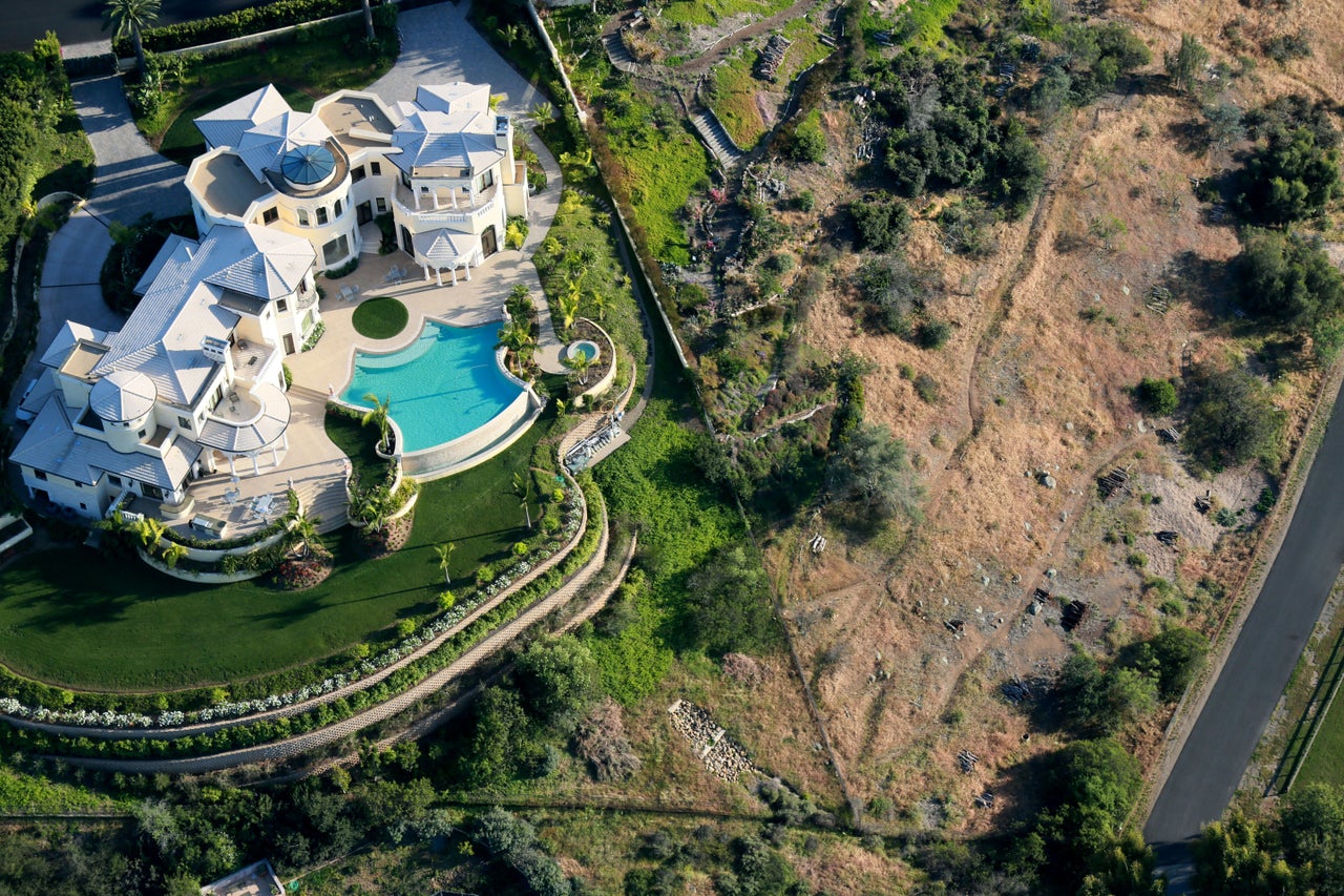 A home with a pool and well-watered garden next to landscape dried out by drought in San Diego.