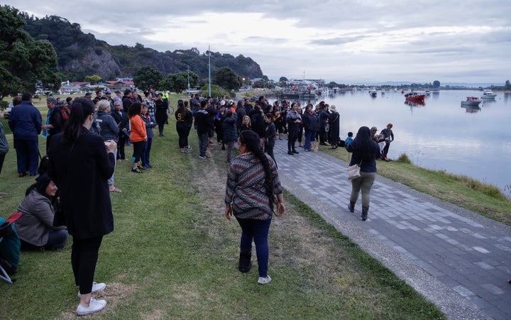 Locals sing during sunrise as they wait for the return of the victims after the White Island eruption to be returned to Whaka