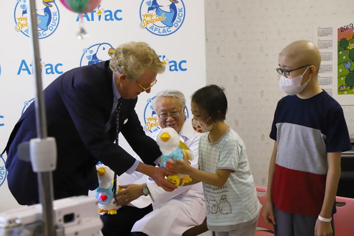 米国アフラックのCEOから、アヒル型ロボット「My Special Aflac Duck」を受け取る子どもたち