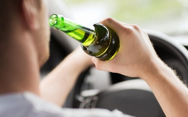Un hombre ingiriendo alcohol al volante, en una imagen de