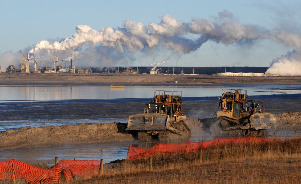 Workers use heavy machinery at a composite tailings pit at the Syncrude oilsands extraction facility near Fort McMurray, Alta. on Oct. 25, 2009. Imperial Oil owns 25 per cent of the development.