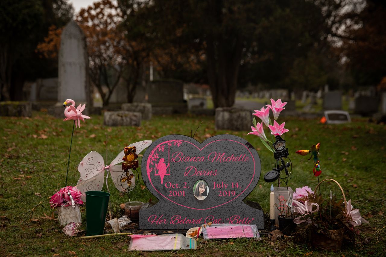 The headstone for Bianca Devins is covered in flowers and tokens from friends and family.