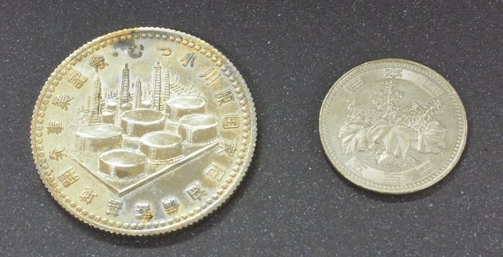 謎のメダル（左）と500円硬貨の比較。こちらの面には「むつ小川原国家石油備蓄基地開発記念」と刻印されている。