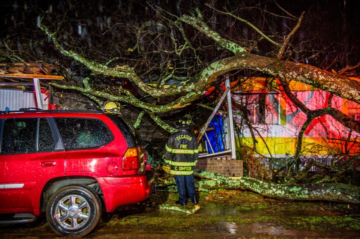 Cory Simpson of Decatur Fire & Rescue assess damage before evacuating a mobile home after a tree fell on the home in Deca