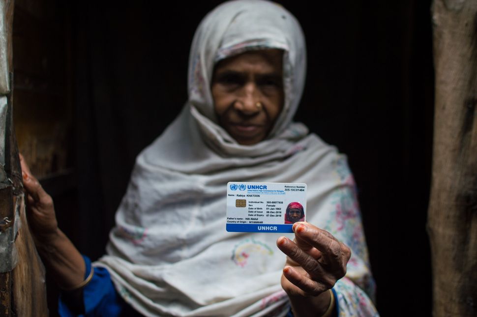 A Rohingya woman, who fled from ongoing military operations in Myanmars Rakhine state, holds up her refugee card issued by the UNHCR at a refugee camp in Madanpur Khadar district of Delhi, India on September 22, 2017.