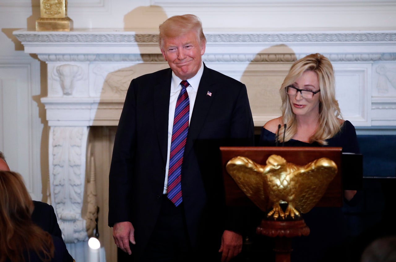 Trump smiles as Paula White prepares to lead the room in prayer during a dinner for evangelical leaders in the State Dining Room of the White House on Aug. 27, 2018.