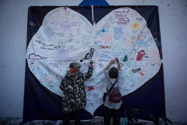 Women write messages on a banner during a memorial service to remember those who have died in the province as a result of the drug overdose crisis, on International Overdose Awareness Day in Vancouver's Downtown Eastside on Aug. 31, 2017. 