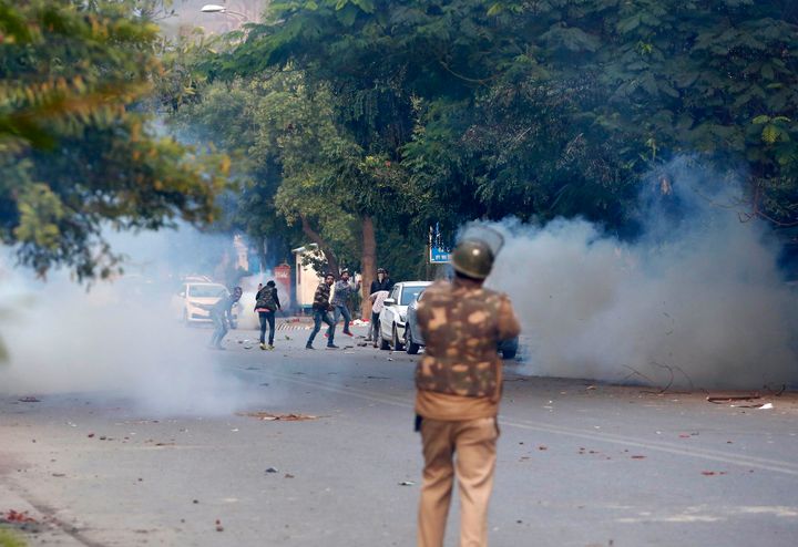 A police personnel fires tear gas to disperse demonstrators protesting against the Citizenship Amendment Act (CAA) at New Friends Colony on December 15, 2019 in New Delhi, India. 