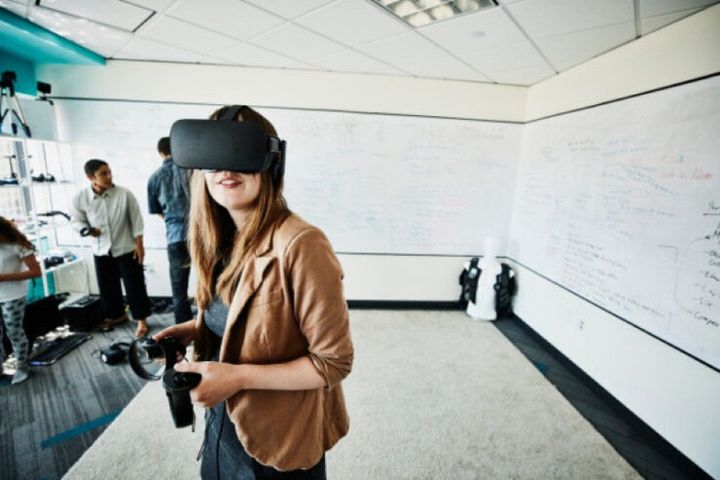 Female engineer using virtual reality headset in computer lab