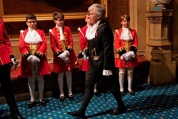 Black Rod, Sarah Clarke the first woman to serve in the role of Black Rod, walks past page boys in the Norman Porch at the Palace of Westminster for the State Opening of Parliament in the Houses of Parliament.