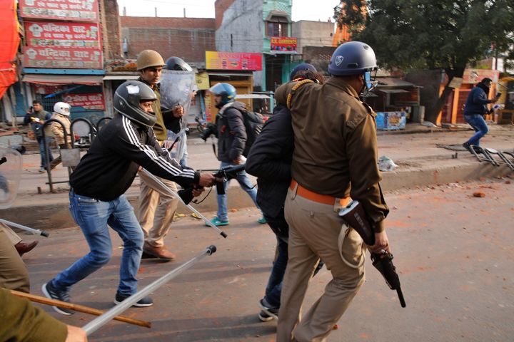 A plain clothes policemen, left, uses a gun to beat from behind a protestor who is detained during protests against India's new citizenship law in Lucknow, India, Thursday, Dec. 19, 2019. 