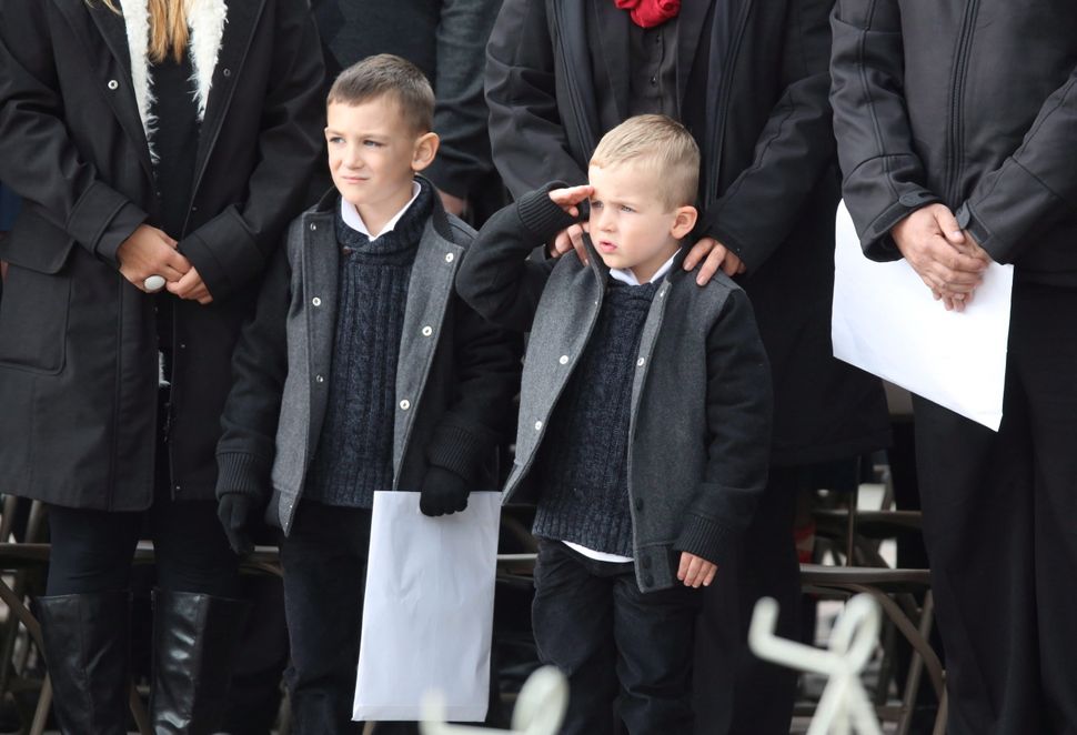 Marcus Cirillo (left), son of Cpl. Nathan Cirillo, stands next to Cameron Cirillo as he salutes during a ceremony marking the one year anniversary of the attack on Parliament hill on Oct. 22, 2015 at the National War Memorial in Ottawa.