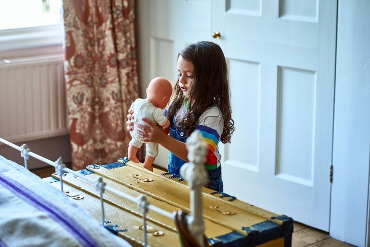 Una niña jugando con un muñeco. 