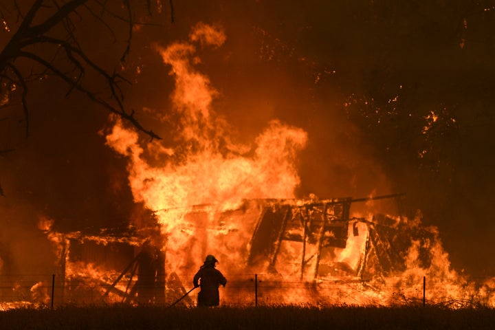 In this Saturday, Dec. 21 ,2019, photo, NSW Rural Fire Service crews fight the Gospers Mountain Fire as it impacts a structure at Bilpin. Australian Prime Minister Scott Morrison on Sunday, Dec. 22, apologized for taking a family vacation in Hawaii as deadly bushfires raged across several states, destroying homes and claiming the lives of two volunteer firefighters.(Dan Himbrechts/AAP Images via AP)