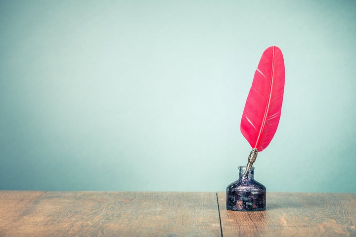 Vintage old red quill pen with inkwell on wooden table front gradient mint green wall background. Retro style filtered photo