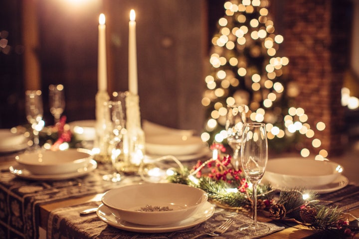 Table set up for Christmas dinner. Evening or night. Christmas tree in background.