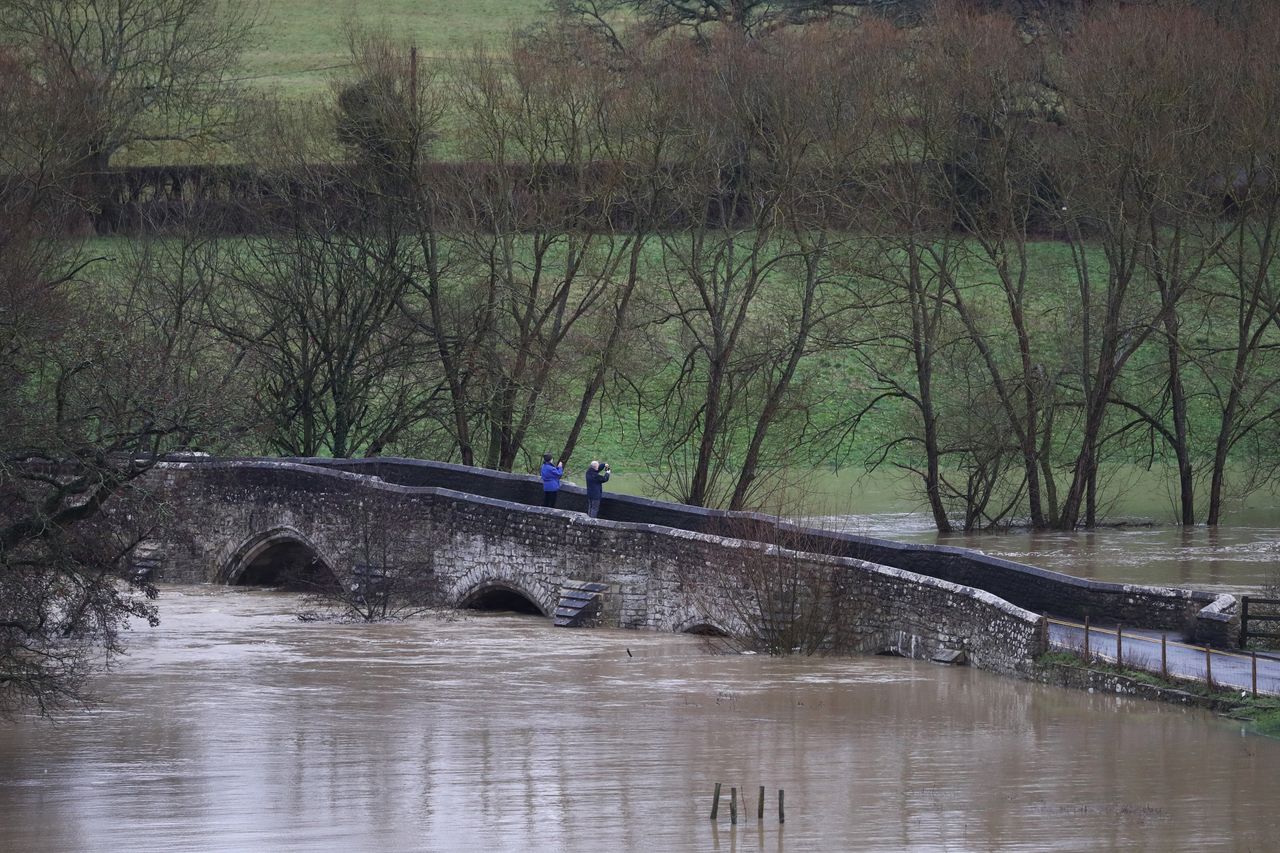 A couple take a photograph of flooding from Teston Bridge in West Farleigh.