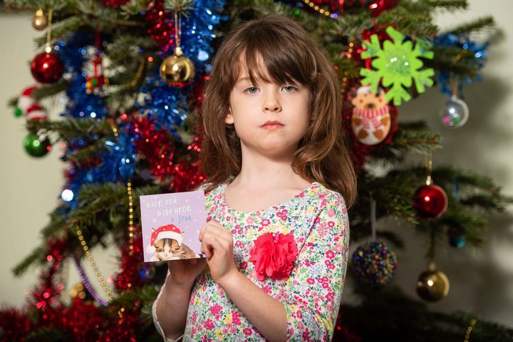 Six-year-old Florence Widdicombe poses Sunday in London with a Tesco Christmas card from the same pack as a card she found containing a message believed to be from a prisoner in China.