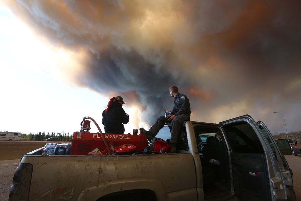 A group trying to rescue animals from Fort McMurray, Alta., wait at a road block as smoke rises from a forest fire on May 6, 2016.